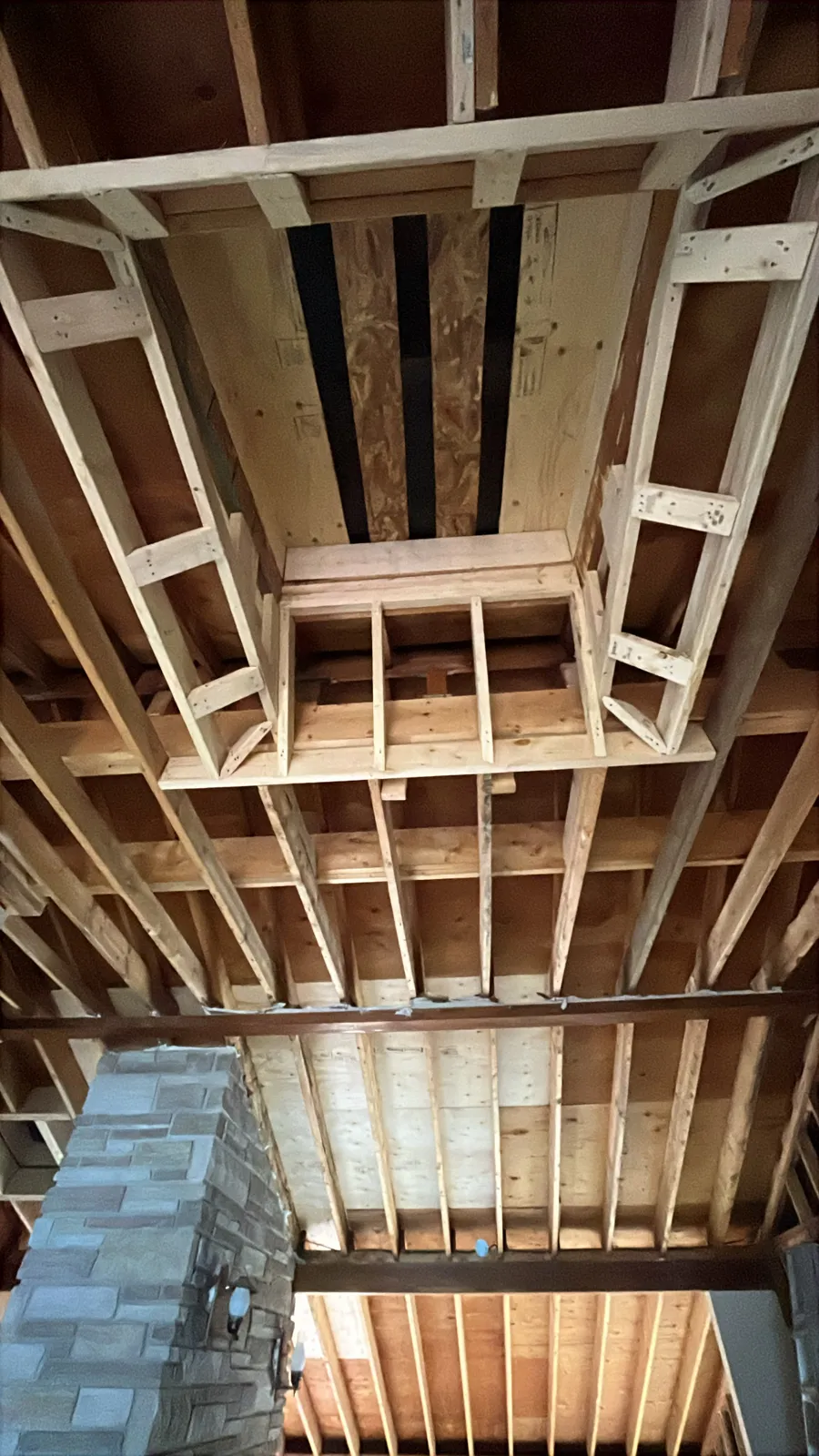 Ceiling framing beside a stone fireplace